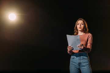 beautiful young actress reading scenario on black