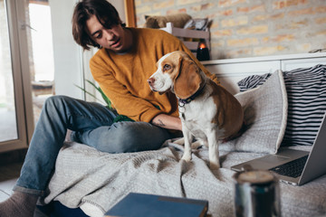 young man playing with his dog in room at home