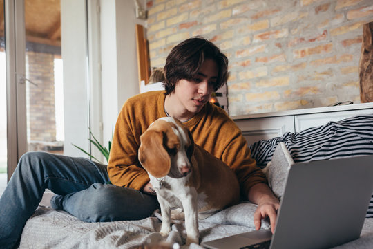 Young Man Playing With His Dog In Room At Home