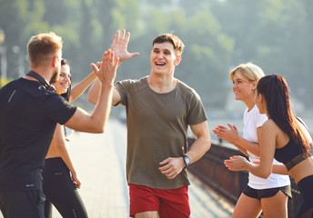 Guy runner runs fun with a group of friends in a park