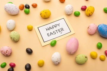 Card with happy easter lettering and bright candies on beige background