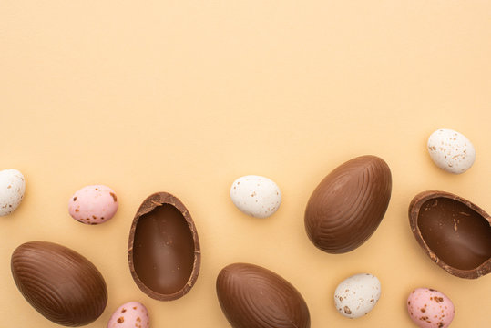 Top view of quail and chocolate eggs on beige background