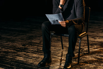 cropped view of african american actor holding scenario on stage during rehearse - obrazy, fototapety, plakaty