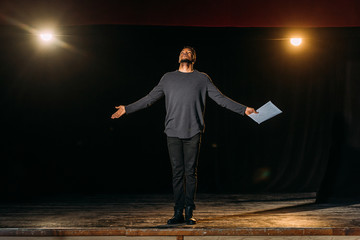 african american actor holding scenario and standing on stage during rehearse - obrazy, fototapety, plakaty