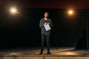 african american actor holding scenario and standing on stage during rehearse