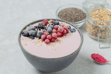 Healthy breakfast berry smoothie bowl topped with frozen blueberries, currants red, blackberries, raspberries, Chia seeds and granola. 