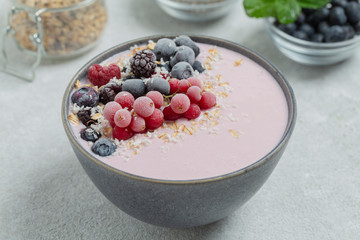 Healthy breakfast berry smoothie bowl topped with frozen blueberries, currants red, blackberries, raspberries, Chia seeds and granola. 