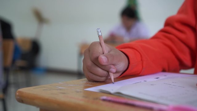 Student hand testing doing test exam with pencil drawing selected choices on answer sheet in school final exams at college or university. Taking multiple choice for assessment in examination classroom
