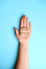 Phrase Me Too made of wooden letters in hand on blue background, top view. Stop sexual assault. Space left for text, copy