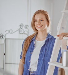 Beautiful young woman on a white wooden stepladder. Ready to repair the room. Women housework concept