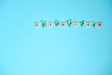 Word gender depicted by using wooden blocks and flowers on colorful blue background