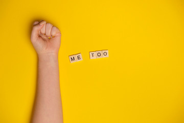 MeToo on wooden alphabet, used for concept of sexual harrassment. Woman fist as protest in shot