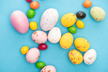 Fototapeta na wymiar Top view of bright colorful sweets and easter eggs on blue background