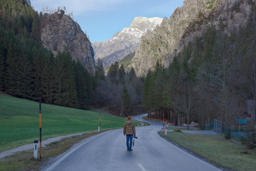 Man walking on the road with beautiful mountain view in Johnsbach village in The Gesause National Park, in Styria region,
