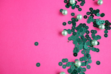 Juicy pink background with light green beads and green sequins. Festive background. Texture
