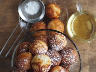 Homemade baking donuts. Deep-fried, in vegetable oil in a frying pan. Holiday and everyday food. Top view. Brown wooden background.