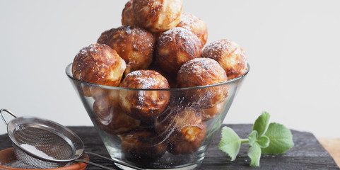Homemade baking donuts. Deep-fried, in vegetable oil in a frying pan. Holiday and everyday food. Place for text. Brown wooden background.