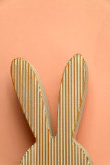 Wooden Easter bunny decoration in front of pastel pink background.