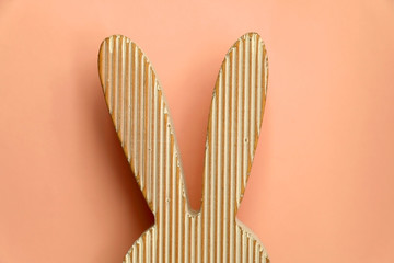 Wooden Easter bunny decoration in front of pastel pink background.