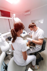 Dentists very carefully check up and repair tooth of young female patient in safety glasses.