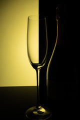 Empty champagne glass with reflection, on a yellow and black gradient background. Club life concept.