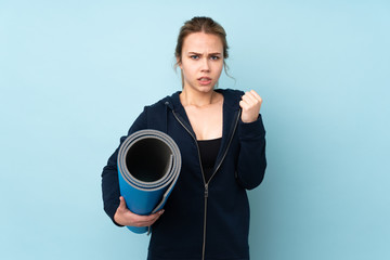 Teenager Russian girl holding mat isolated on blue background frustrated by a bad situation