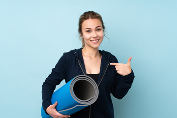 Teenager Russian girl holding mat isolated on blue background with surprise facial expression