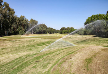 A large Golf course with a perfectly manicured lawn. The lawn needs watering. Lawn irrigation system on the Golf course.