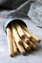 Traditional italian breadsticks grissini with flax seeds on a gray background.