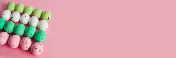 Colorful quail eggs, easter banner on pink background. Copy space.