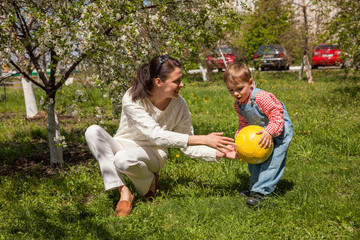 Happy mom and her three year old son play on the grass in spring