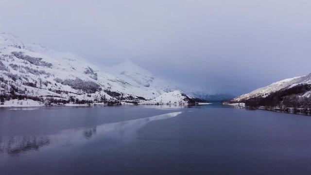 aerial drone footage of winter in glencoe and and loch leven in the argyll region of the highlands of scotland showing clear bright white snow on the mountains of glencoe and the surrounding region
