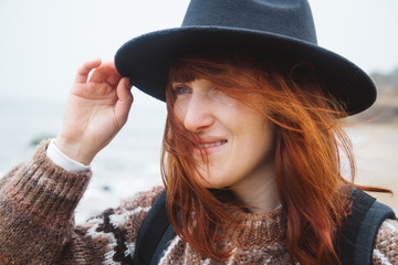 Portrait of a beautiful red-haired woman in a hat. Place for text or advertising