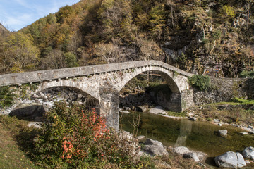Fototapeta na wymiar BIGNASCO, SWITZERLAND - OCTOBER 24, 2017: A picturesque village in a valley Maggia, canton Ticino. Special are the ancient stone bridge and the church from 15th century.