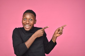 handsome young black man looking excited and pointing to space on his side with both hands