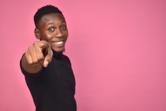 handsome young black man looking excited and pointing to forward towards the camera