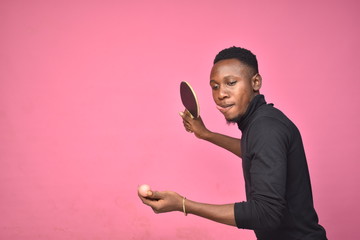 handsome young black man holding a table tennis ball in hand ready to serve