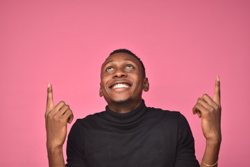 handsome young black man looking excited and pointing above and looking up