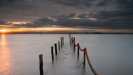Fototapeta premium Torreira old pier in a stormy sunrise