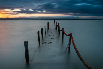 Obraz premium Stary molo w Torreira o wschodzie słońca i burzliwym niebie