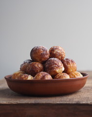 Homemade baking donuts. Deep-fried, in vegetable oil in a frying pan. Holiday and everyday food. Place for text. Brown wooden background.