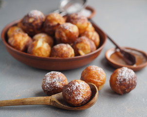 Homemade baking donuts. Deep-fried, in vegetable oil in a frying pan on a gray table. Holiday and everyday food. Place for text.