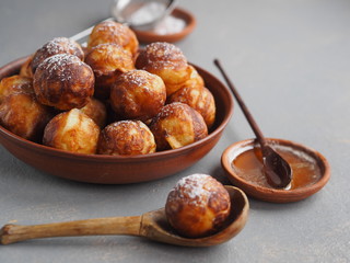 Homemade baking donuts. Deep-fried, in vegetable oil in a frying pan on a gray table. Holiday and everyday food. Place for text.