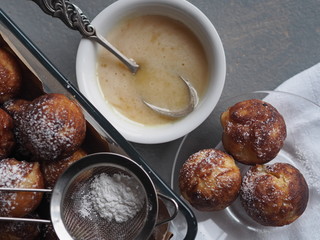 Homemade baked donuts on a gray background in a glass form for the oven with a strainer with icing sugar.