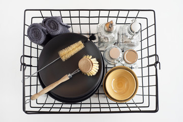 Basket with kitchen utensils, plates, glass bottles, a granny brush for washing dishes, towels on white background. Zero Waste concept. Top view