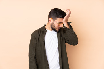 Caucasian handsome man isolated on beige background with headache
