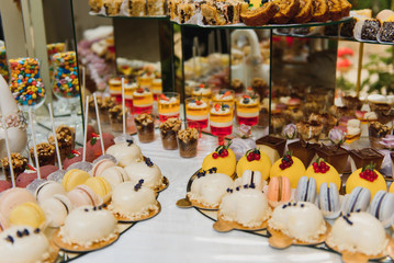 Delicious sweets on wedding candy buffet with desserts, cupcakes,tiramisu and cookies