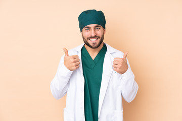 Surgeon man isolated on beige background giving a thumbs up gesture
