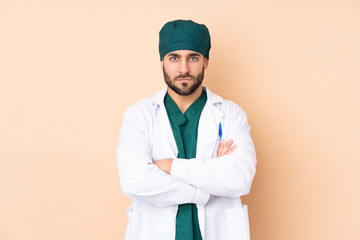 Surgeon man isolated on beige background keeping arms crossed