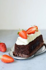 Chocolate brownie with airy vanilla cream and fresh strawberries. Chocolate cake with cream and fresh berries. Tea dessert